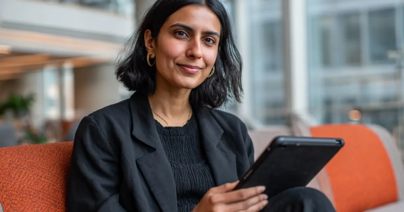Professional woman in business attire holding tablet in modern office workspace