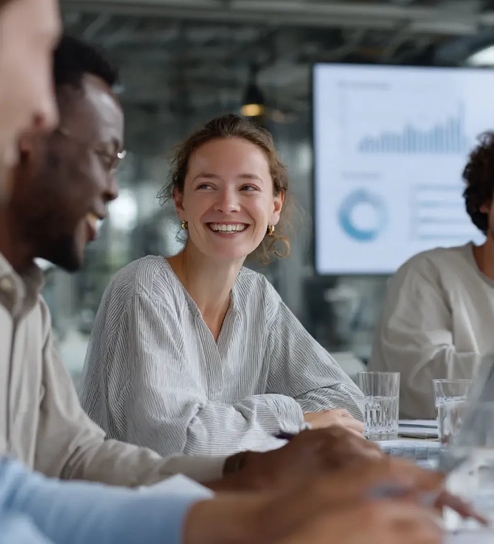 Professional woman smiling during compliance team meeting with data presentation in modern office