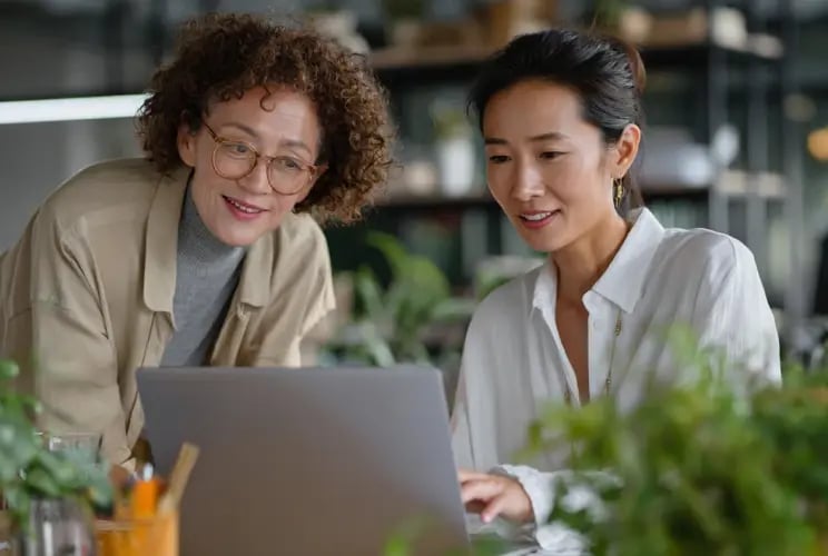 Two professionals collaborating on laptop reviewing fund administration services in modern office setting