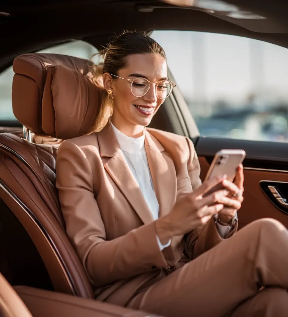 Professional woman in luxury car using smartphone for private wealth management services