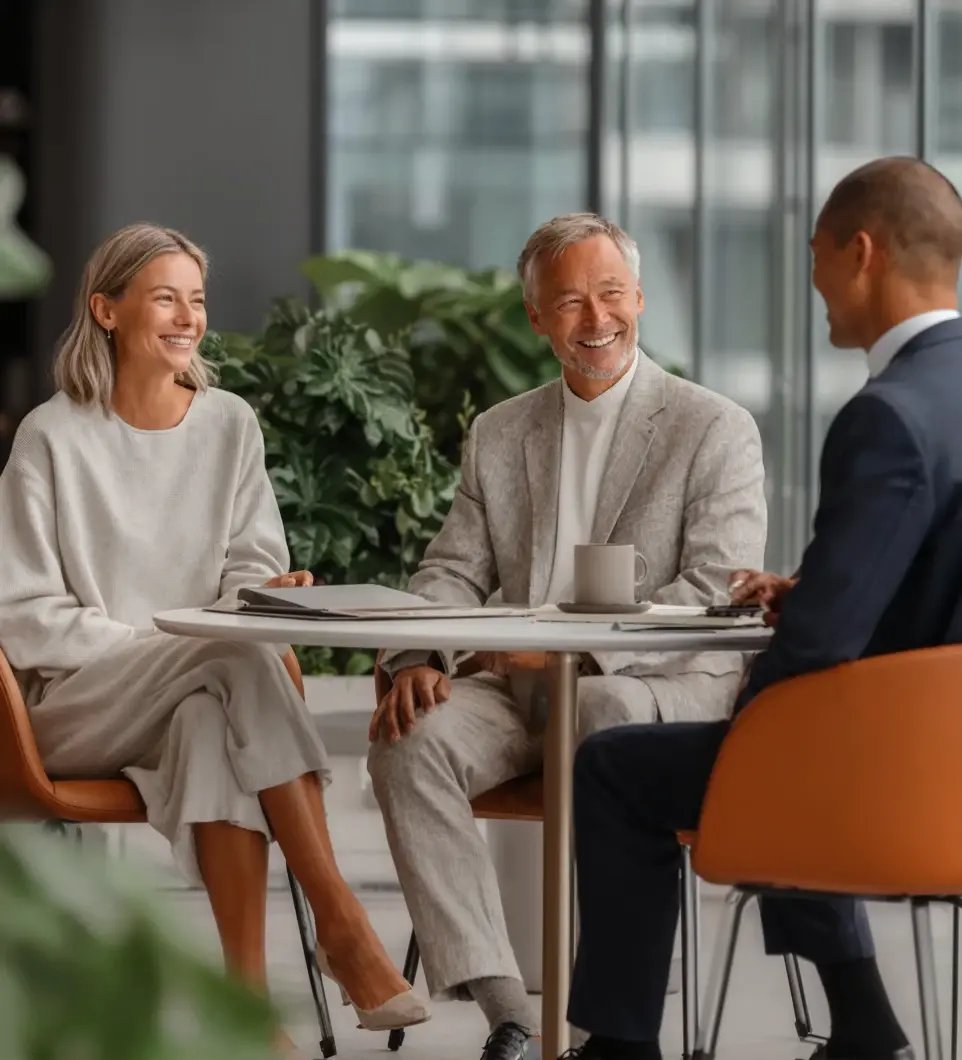 Three professionals having a business meeting in modern office with natural light and greenery