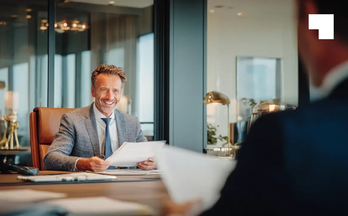 Businessman reviewing documents with client during corporate advisory meeting in modern office