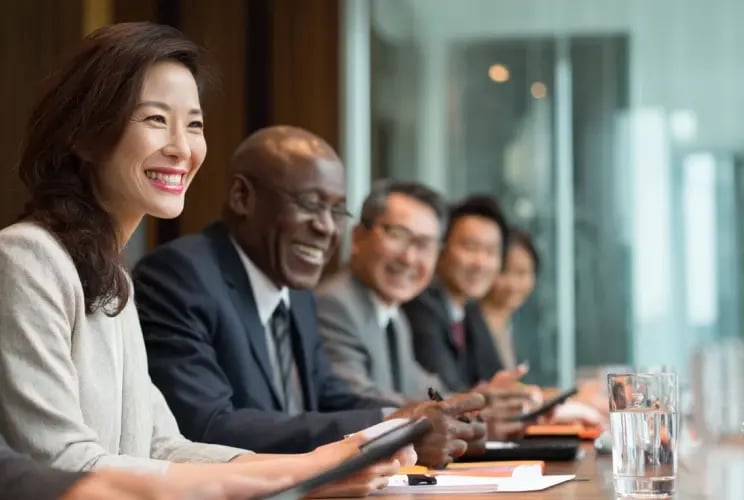 Diverse business professionals smiling during corporate board meeting in modern conference room