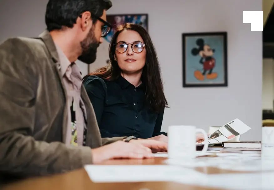 Two financial advisors reviewing wealth management documents at modern office desk