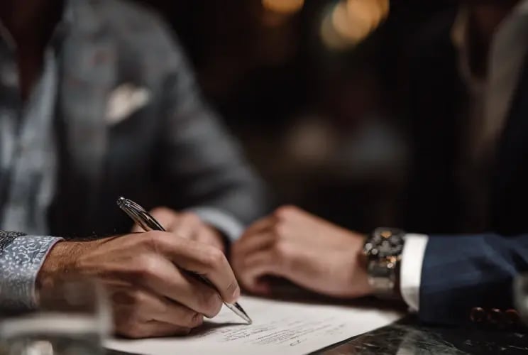 Two professionals signing estate planning and trust documents at a business meeting