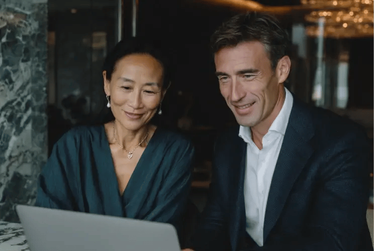 Two professionals reviewing wealth planning documents on laptop in modern office setting