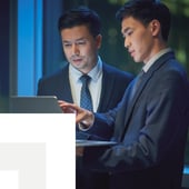 businessmen discussing and pointing at a laptop