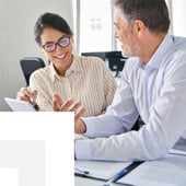 businesswoman and businessman looking at a tablet