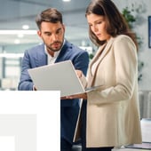 Businesswoman and businessman reviewing documents on laptop