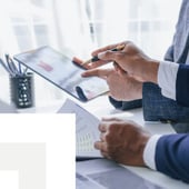 Hand pointed at a tablet in a business meeting